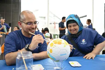 Setiausaha Parlimen Kanan (Pendidikan merangkap Pembangunan Negara), Dr Syed Harun Alhabsyi (kiri) dan pelatih Minds Craft, Cik Siti Farhana Borhan, bersama-sama melukis bola sepak di Perarakan Stokin Warna Minds 2026.
