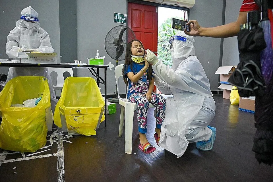 JALANI UJIAN COVID-19: Seorang kanak-kanak sedang menjalani ujian mengesan Covid-19 secara percuma di sebuah pusat pemeriksaan koronavirus di Shah Alam, sedang kes jangkitan di Malaysia terus meningkat. - Foto AFP