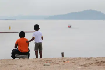 Dua beradik memerhatikan sebuah bot. 