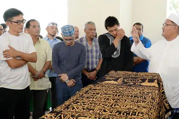 PENGHORMATAN TERAKHIR: Bekas kapten pasukan Singapura dan adik kepada Allahyarham Amin, Nazri Nasir (kiri) serta anak Allahyarham yang bermain bagi kelab Balestier Khalsa, Ashrul Syafeeq (berbaju hitam), kelihatan pilu dengan pemergian Allahyarham. - Foto ZAINAL YAHYA