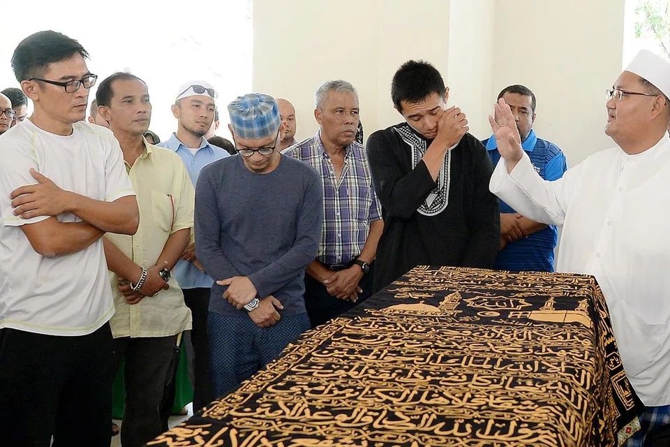 PENGHORMATAN TERAKHIR: Bekas kapten pasukan Singapura dan adik kepada Allahyarham Amin, Nazri Nasir (kiri) serta anak Allahyarham yang bermain bagi kelab Balestier Khalsa, Ashrul Syafeeq (berbaju hitam), kelihatan pilu dengan pemergian Allahyarham. - Foto ZAINAL YAHYA