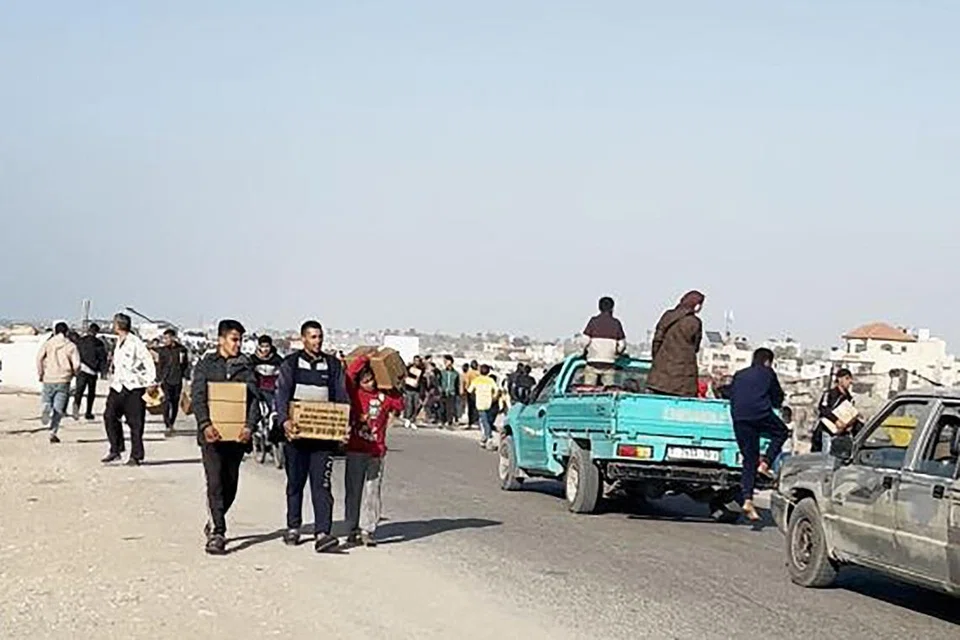 Orang ramai membawa bungkusan makanan yang digugurkan dari pesawat Amerika di atas pantai di Jaluran Gaza pada 2 Mac. Sekutu utama Israel, Amerika Syarikat, berkata ia memulakan bantuan yang digugurkan dari udara.