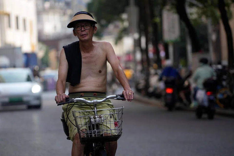 BERLENGENG: Lelaki ini menanggalkan bajunya ketika berbasikal di sebatang jalan raya di Shanghai, China, pada 11 Julai, kerana cuaca terlalu panas.