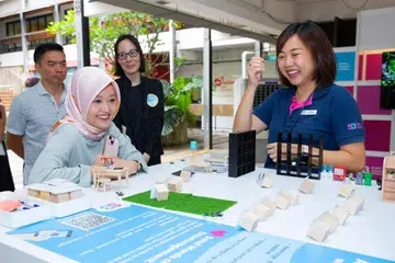 Menteri Negara (Penerangan dan Pembangunan Digital merangkap Kesihatan), Cik Rahayu Mahzam (depan, kiri), membincangkan contoh gim adaptif atau mudah suai, yang akan dibuka pada 2025, bersama Pengarah Eksekutif Stesen Sokongan Strok (S3), Cik Ng Rei Na (kanan), pada 24 Oktober.