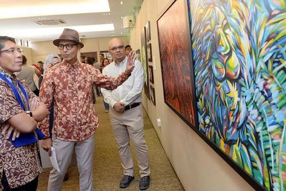 MENIKMATI SENI: Encik Abu Jalal Sarimon (bertopi) menerangkan kepada Dr Mohamed Maliki Osman (kiri) tentang hasil kerjanya yang bertajuk 'Singa Di Puncak Larangan' di samping Presiden Apad, Encik Kamal Dollah (kanan). 