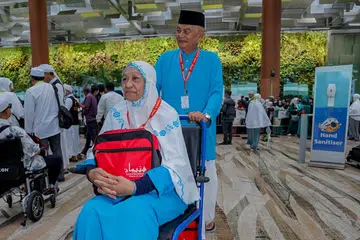 TEKAD TUNAI HAJI: Cik Norati Bakar, 55 tahun, disorong oleh suaminya Encik Ahmad Abdul Karim, 66 tahun, sebelum berangkat untuk menunaikan ibadah haji pada Isnin.