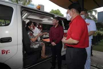 KLINIK TCM BERGERAK: Seorang penduduk GRC East Coast (duduk dalam van) berbual dengan (dari tengah) Dr Maliki Osman, DPM Heng Swee Keat dan Ketua Pengarah Tao One, Encik Andy Wong, sambil menunggu rawatan TCMnya dalam Klinik TCM Bergerak GRC East Coast. - Foto BH oleh ALPHONSUS CHERN