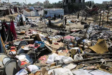 Pelarian Palestin memeriksa barang mereka yang rosak selepas bedilan Israel di kem Al-Mawasi, Khan Younis di  selatan Jaluran Gaza pada 13 Julai. 