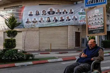 Seorang lelaki duduk di sebelah sepanduk kempen pilihan raya yang memaparkan calon bagi Ramallah dan Al-Bireh menjelang pilihan raya perbandaran, di bandar Ramallah di Tebing Barat yang diduduki Israel.