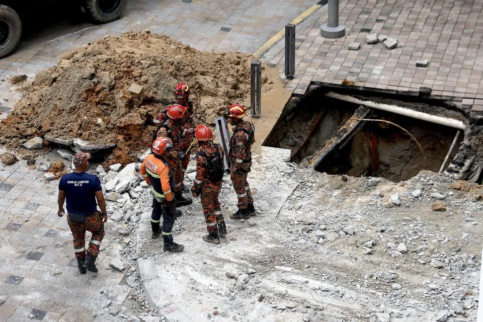 OPERASI MENCARI: Pegawai bomba kelihatan meninjau lubang tanah jerlus pertama yang berlaku pada 23 Ogos, di mana seorang wanita disahkan terjatuh di dalamnya. Operasi mencari dan menyelamat (SAR) bagi mangsa itu telah dihentikan pada 31 Ogos