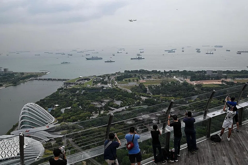 RAKAM PERTUNJUKAN: (Kanan) Orang ramai di Dek Pemerhatian SkyPark di Marina Bay Sands mengambil gambar tiga jet F-15SG di perairan Marina South semalam. (Gambar sisipan) Jet F16C/D dan F-15SG Angkatan Udara Republik Singapura (RSAF) melakukan terbang lalu dalam bentuk Formasi Delta di perairan Marina South semalam. 
