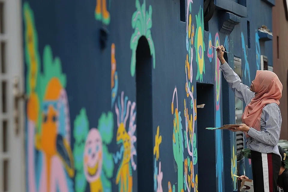 SENI KREATIF: Seorang pelukis melahirkan karya seninya di tembok di Kampong Glam.