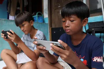 Affan Haritsah, 11 tahun, dan Kevin Prince, 14 tahun, bermain permainan di telefon bimbit mereka ketika Kementerian Komunikasi dan Digital Indonesia melaksanakan sekatan terhadap platform media sosial berisiko tinggi seperti Facebook, TikTok dan Roblox, di Depok, pinggir Jakarta, Indonesia, 28 Mac 2026.