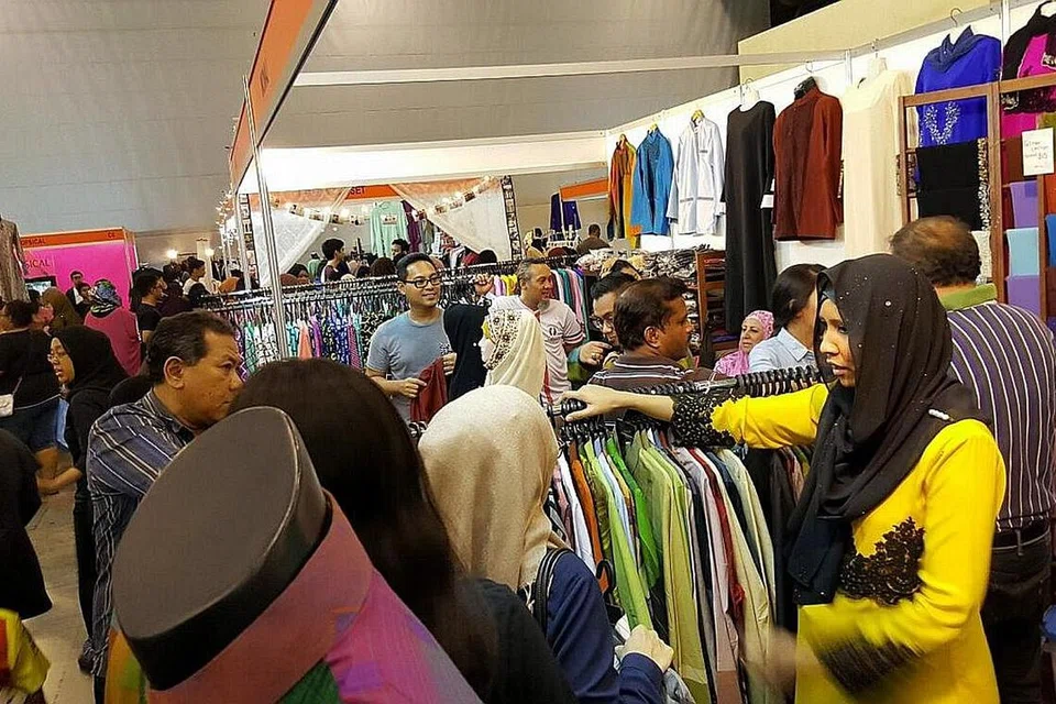LEBIH RANCAK: Penjualan pakaian Raya di gerai ExpoRaya lebih rancak berbanding di bazar Geylang Serai, menurut pemilik Jihan by Mona J, Cik Jihan Jauhar (berbaju kuning). Kedai beliau di Geylang Serai terletak di kawasan Engku Aman. - Foto ihsan JIHAN JAUHAR 