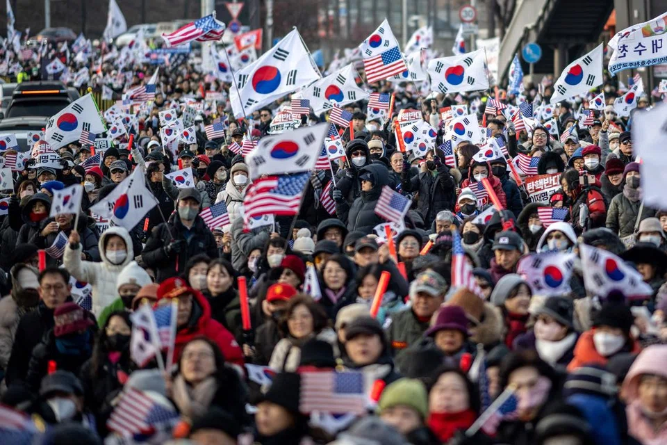 Penyokong Presiden Korea Selatan yang digantung tugas, Encik Yoon Suk Yeol, mengibarkan bendera Amerika dan Korea Selatan dekat kediaman Presiden di Seoul pada 1 Januari.