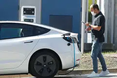 BERSAMA TANGANI PEMANASAN GLOBAL: Seorang lelaki memeriksa telefon bimbit sementara beliau mengecas kereta elektrik Tesla di Sant Cugat del Valles, berdekatan Barcelona, Sepanyol. - Foto REUTERS