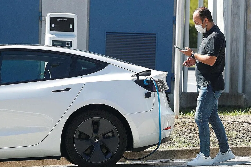 BERSAMA TANGANI PEMANASAN GLOBAL: Seorang lelaki memeriksa telefon bimbit sementara beliau mengecas kereta elektrik Tesla di Sant Cugat del Valles, berdekatan Barcelona, Sepanyol. - Foto REUTERS