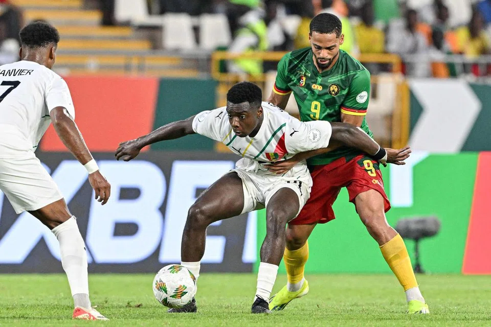 SAINGAN SENGIT: Pemain pertahanan Guinea Sekou Sylla (jersi putih) berebut bola dengan penyerang Cameroon, Franck Magri (jersi hijau). Magri akhirnya berjaya menjaringkan gol hasil tandukannya pada minit ke-51 untuk menyamakan kedudukan buat Cameroon.