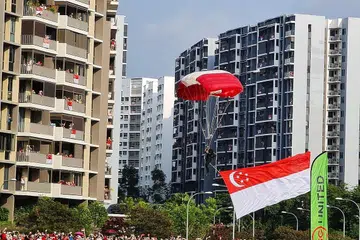 LIHAT DARI DEKAT: Ramai berkumpul untuk menyaksikan aksi terjun bebas 'Red Lions' yang mendarat di padang lapang bersebelahan Hospital Besar Sengkang. - Foto BH oleh KELVIN CHNG 