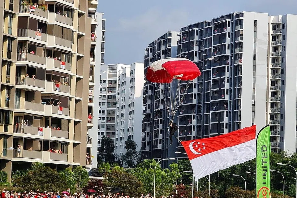 LIHAT DARI DEKAT: Ramai berkumpul untuk menyaksikan aksi terjun bebas 'Red Lions' yang mendarat di padang lapang bersebelahan Hospital Besar Sengkang. - Foto BH oleh KELVIN CHNG 