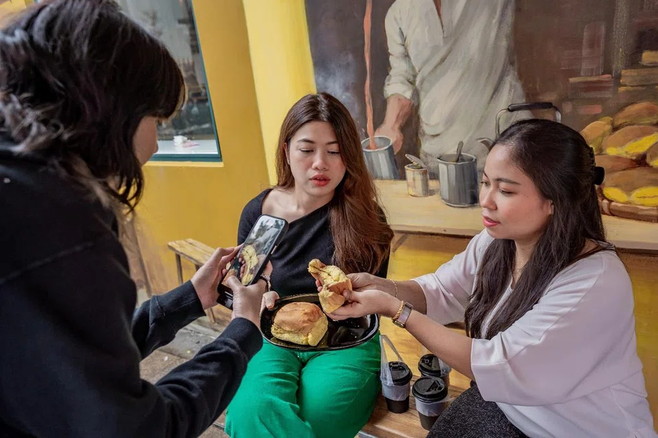 Wartawan ruangan Kaki Makan, Dahlia Zulkifli (tengah) dan Nur Syuhrah Hassan (kanan) membuat reviu ‘roti kahwin’ yang dijual di kedai Tarik di Arab Street. Bersama dalam gambar ialah penyunting video, Syaheera Azlan (kiri).