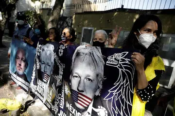 PENDAKWAAN ASSANGE: Penunjuk perasaan memegang sepanduk yang menunjukkan gambar Assange, sedang pemerintah Mexico bersedia menawarkan tempat berlindung politik kepada Assange, sewaktu tunjuk perasaan di luar Kedutaan United Kingdom di Mexico City kelmarin. - Foto REUTERS