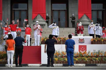 TABIK HORMAT: Presiden Halimah Yacob (kanan), Perdana Menteri Lee Hsien Loong (bertopi putih) dan Anggota Parlimen lain memberi penghargaan mereka kepada petugas di barisan hadapan di Perbarisan Hari Kebangsaan di Padang pagi semalam. - Foto BH oleh NG SOR LUAN