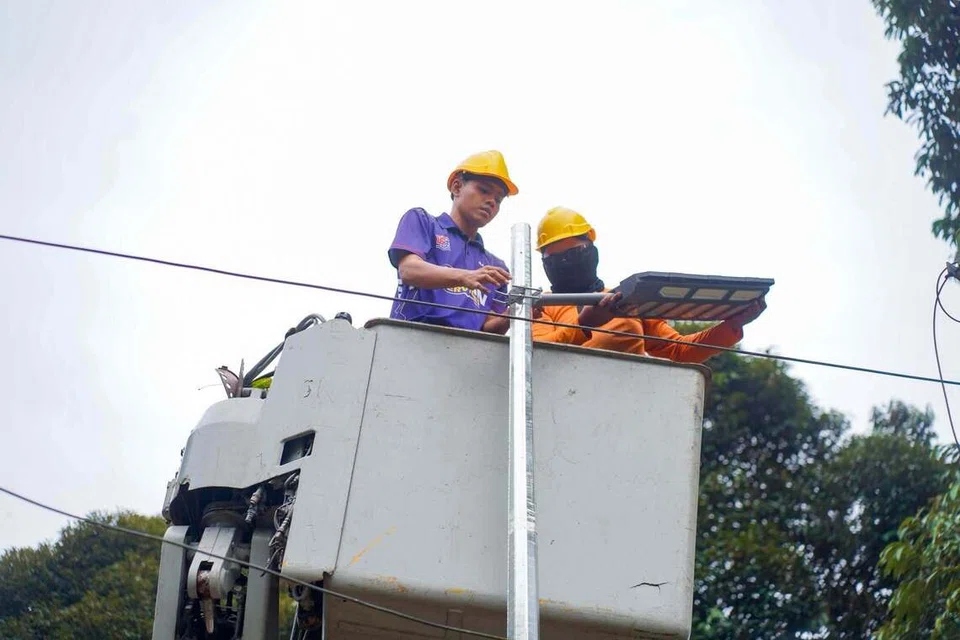 Pekerja memasang lampu berkuasa suria pada tiang di Kampung Gelang Chinchin, Segamat.