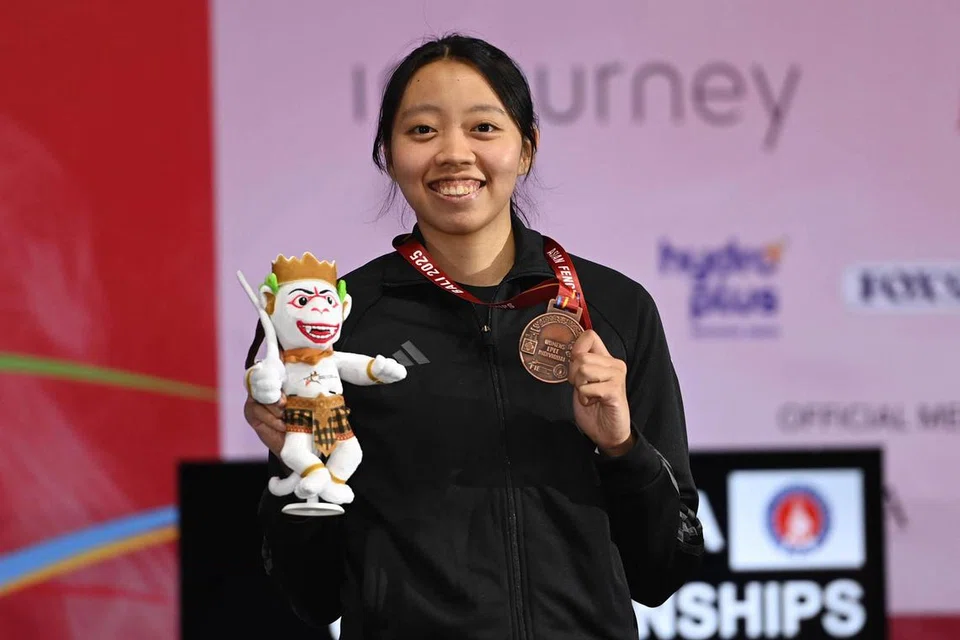 Atlet lawan pedang negara, Kiria Tikanah Abdul Rahman, tersenyum sambil memegang pingat gangsa yang dimenanginya dalam acara ‘epee’ individu wanita di Kejohanan Lawan Pedang Asia 2025 di Bali, Indonesia.