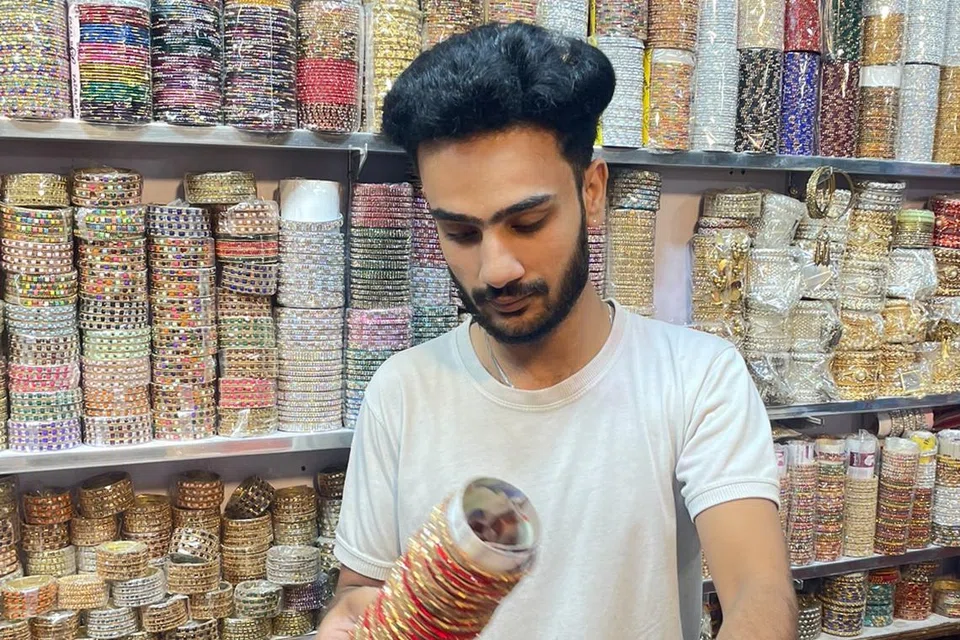 Penjual gelang plastik di Bazar Anarkali yang menawarkan kepelbagaian dan memberikan pengalaman berbelanja yang menakjubkan. 