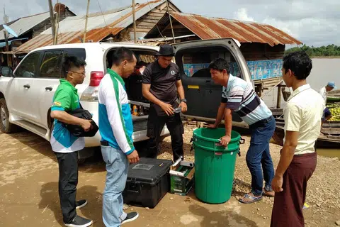 SALING BEKERJASAMA: Encik Azat Khan Mukarab Khan (tengah) membantu bawa sistem rawatan air mudah alih yang kelihatan seperti bagasi besar itu. Sistem tersebut dihasilkan syarikat Aquana dan dibawa ke Myanmar untuk memudahkan penduduk mendapatkan air bersih. - Foto AQUAYANA