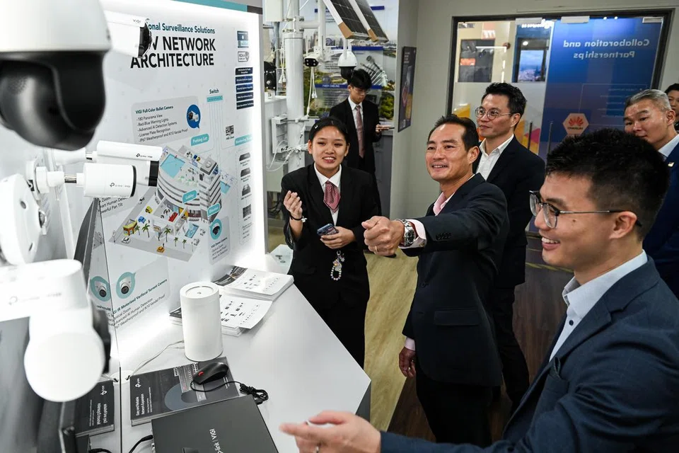 Encik Tan Kiat How (tengah) dan Encik Hugo Cai (kanan) mempelajari teknologi pengawasan bijak seperti kamera keselamatan, daripada pelajar kursus Nitec Lanjutan dalam Kejuruteraan Elektronik di ITE Kolej Timur, Cik Phoebe Goh Pei Ci (kiri).