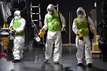 MEMBUAT KERJA-KERJA PEMBERSIHAN: Pekerja Korea Selatan yang mengenakan pakaian pelindung membersihkan teater di Pusat Budaya Sejong di Seoul. - Foto AFP