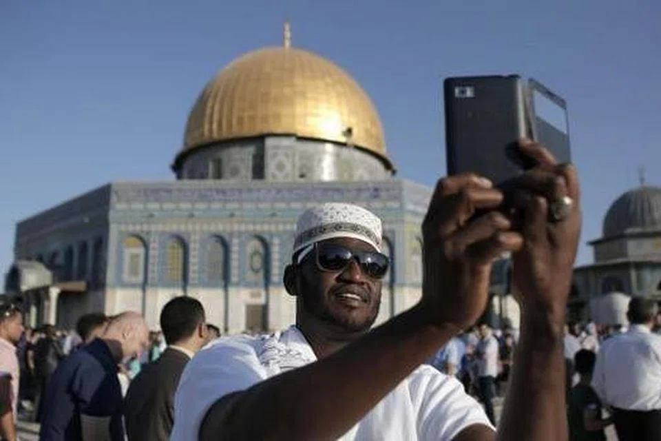 BUAT KENANGAN: Seorang jemaah dari Afrika memetik 'selfie' di hadapan Qubbat As-Sakhrah atau Kubah Batu yang terletak bersebelahan Masjid Al-Aqsa di Baitulmakdis. - Foto AFP