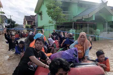 TINGGALKAN RUMAH: Para penduduk mengosongkan rumah mereka di Makassar menyusuli hujan lebat dan angin kencang yang melanda bahagian selatan pulau Sulawesi, menyebabkan air sungai melimpahi tebing membanjiri kawasan di sembilan daerah selatan. Banjir kilat dan tanah runtuh yang berlaku pada hujung bulan lalu itu mengakibatkan puluhan orang terkorban dan ramai terpaksa berpindah. - Foto AFP