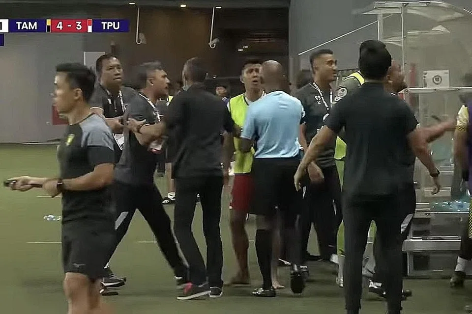 POLIS TERLIBAT: Pemain dan pegawai Tanjong Pagar dilihat cuba ditenangkan daripada bersemuka dengan anggota pasukan Tampines selepas perlawanan liga mereka di Our Tampines Hub malam kelmarin. - Foto TANGKAP LAYAR YOUTUBE LIGA PERDANA SINGAPURA