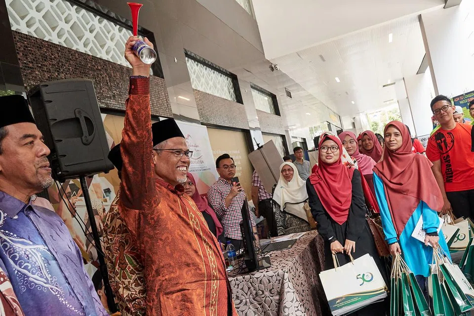 MENGUAR-UARKAN MESEJ MURNI RAMADAN: Encik Masagos Zulkifli menggunakan hon udara bagi melancarkan usaha sekitar 60 sukarelawan mengedarkan risalah dan maklumat mengenai Ramadan kepada orang ramai di serata Orchard Road semalam. Bersama di majlis itu ialah Ketua Eksekutif Muis, Haji Abdul Razak Maricar (kiri). - Foto BH oleh LIN ZHAOWEI