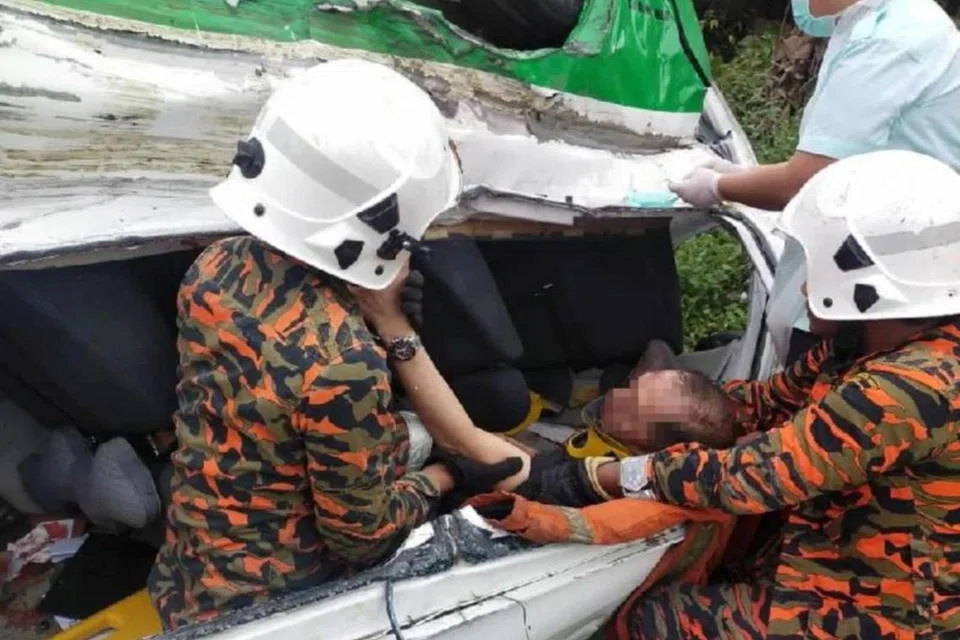 Anggota dari Bomba dan Penyelamat Semporna, Sabah, mengeluarkan mangsa dari van pelancong yang terbabit nahas dengan treler di Jalan Semporna-Tawau, Sabah, pada 11 Mac.