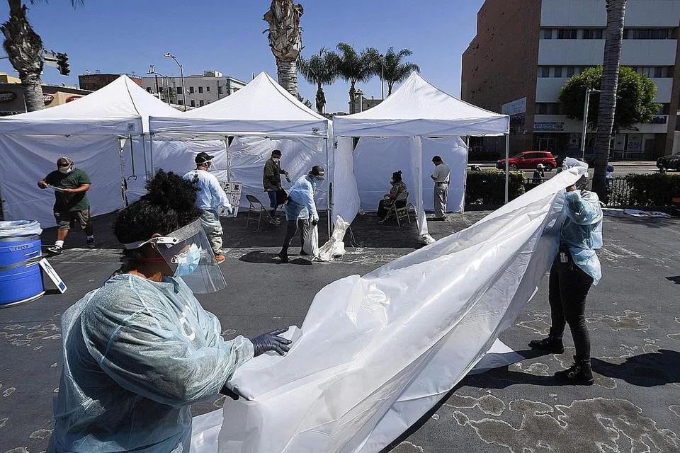 USAHA MENGESAN JANGKITAN: Kakitangan mendirikan sesekat bagi khemah kubikel di sebuah pusat ujian coronavirus Covid-19 di Los Angeles, California, kelmarin. Pegawai Los Angeles County melaporkan 1,920 kes baru Covid-19 kelmarin. Amerika mempunyai kes jangkitan Covid-19 tertinggi di dunia. - Foto AFP