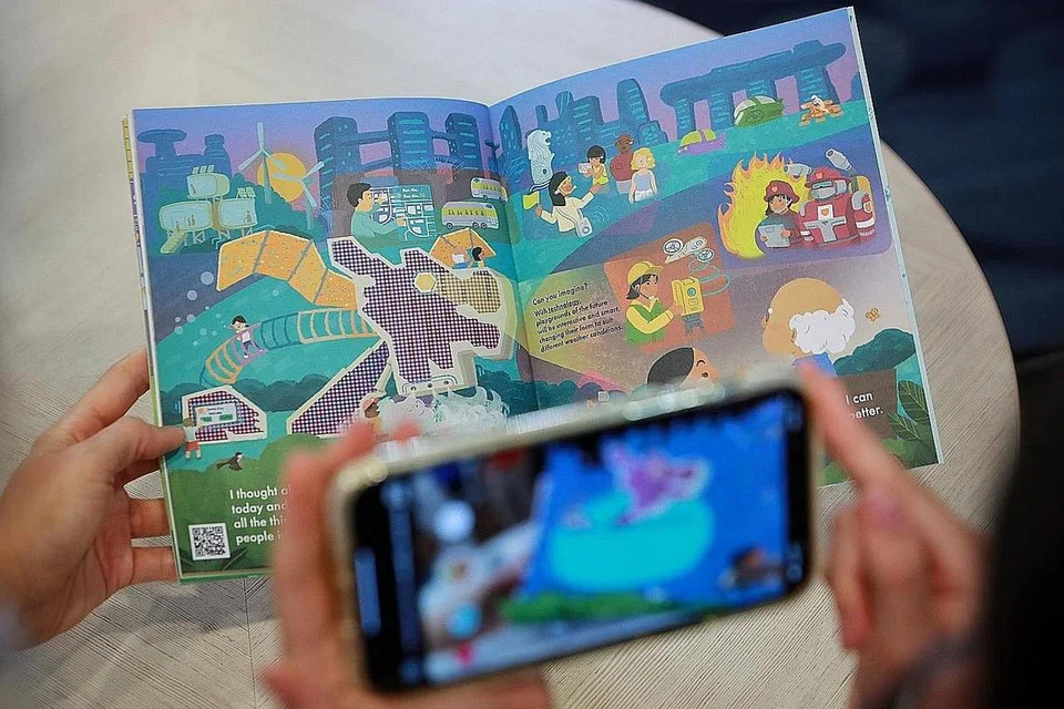 GUNA TEKNOLOGI: Telefon bimbit boleh digunakan untuk mengimbas kod QR yang terdapat di beberapa halaman buku 'My Favourite Days' untuk menjadikan babak dalam buku cerita tersebut satu 'kenyataan'. - Foto BH oleh JASON QUAH