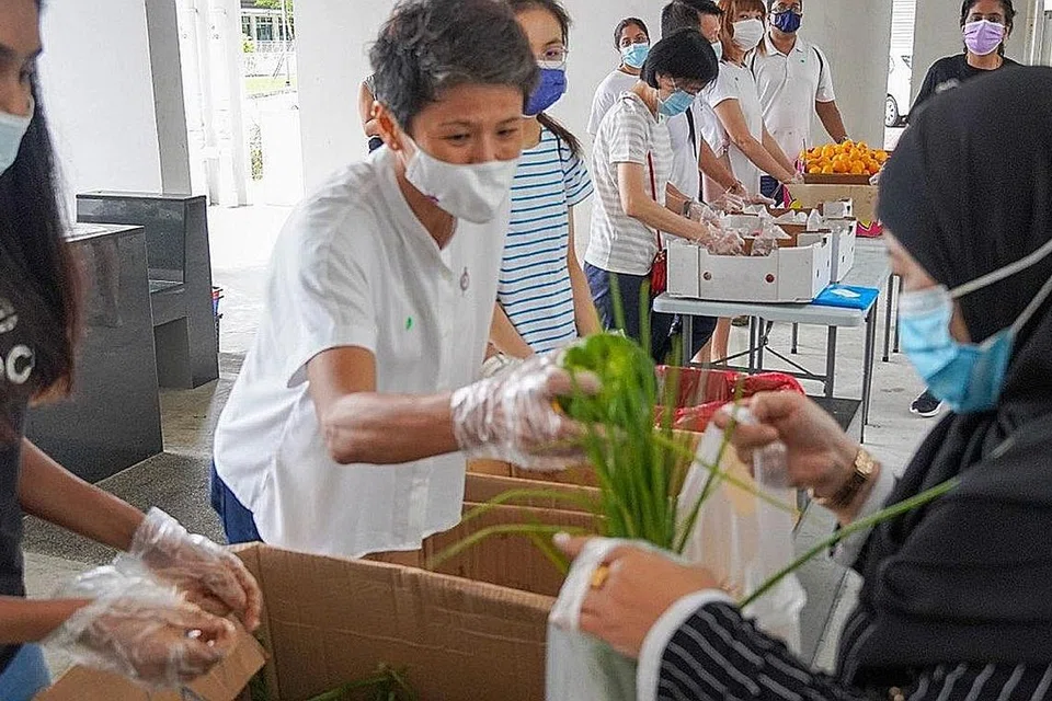 SEBAR MESEJ HIJAU: Cik Poh (tengah) mengagihkan sayur-sayuran yang 'diselamatkan' kepada penduduk di Blok 785A Woodlands Rise pada hujung bulan lalu. - Foto BM oleh ZULAIQAH ABDUL RAHIM 