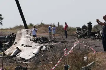 JALANKAN SIASATAN: Seorang penyiasat dari Malaysia (kanan) sedang melakukan kerja siasatan di tapak terhempasnya MH17 berdekatan kampung Hrabove (Grabovo), kawasan Donetsk. - Foto REUTERS
