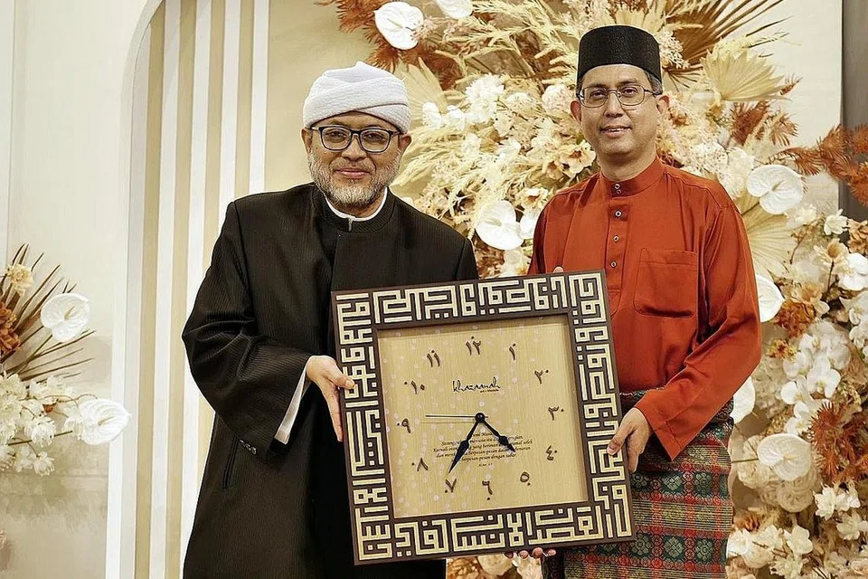 GEMILANG RAYA: Presiden Persatuan Ulama dan Guru-Guru Agama Islam Singapura (Pergas), Ustaz Mohamad Hasbi Hassan (kiri) menyampaikan tanda penghargaan kepada tetamu terhormat, Menteri Negara (Ehwal Dalam Negeri merangkap Pembangunan Negara), Profesor Madya Dr Muhammad Faishal Ibrahim semasa majlis Gemilang Raya anjuran pertubuhan tersebut. - Foto PERGAS
