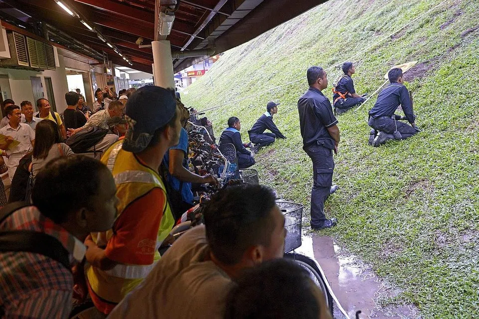 OPERASI HAPUS TIKUS: Orang ramai menyaksikan petugas daripada sebuah syarikat kawalan haiwan perosak semasa satu operasi menghapuskan tikus di sebelah stesen MRT Bukit Batok pada Disember 2014. - Foto fail