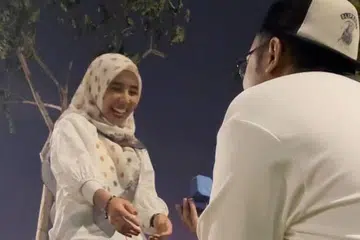 Encik Muhammad Fadzly Hanafe ‘melamar’ isterinya, Cik Siti Aisyah Mohamad Noor semasa pertunjunjukan bunga api dalam menyambut 2026, di belakang Marina Bay Sands.
