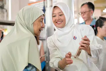 Menteri Negara (Penerangan dan Pembangunan Digital merangkap Kesihatan), Cik Rahayu Mahzam (kanan) sedang beramah tamah dengan seorang penduduk yang telah menginap di Jurong East Street 24 selama 40 tahun, Cik Rokiah Hussen.