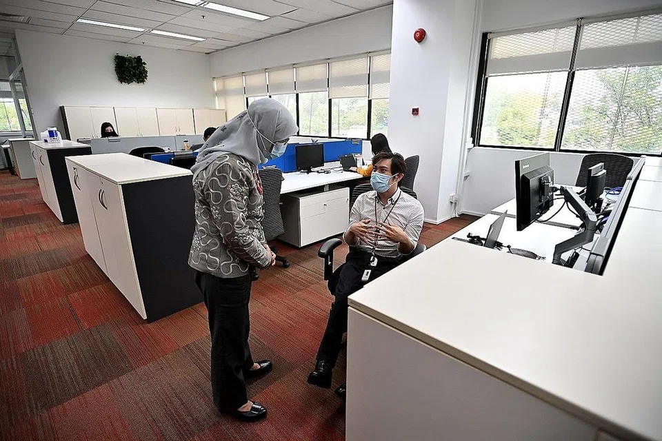 BERAMAH-TAMAH: Presiden Halimah Yacob beramah-tamah bersama Encik Maximillian Tan, 33 tahun, seorang eksekutif sumber manusia yang mengalami palsi serebrum, yang sedang duduk di sebelah meja kerja yang ketinggiannya boleh dilaraskan dan skrin yang boleh dilaraskan, semasa lawatannya ke Cushman and Wakefield Services semalam. - Foto BH oleh LIM YAOHUI