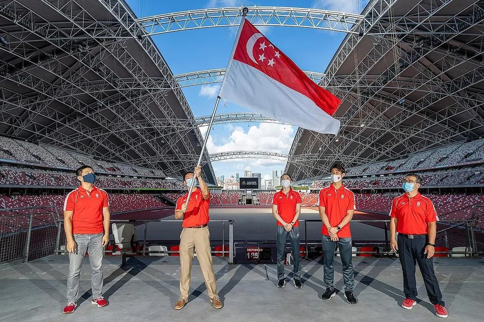 KIBAR BENDERA: Chef-de-mission Dr Ben Tan (dua dari kiri) mengibar bendera Singapura di Stadium Negara semalam. Bersama beliau ialah (dari kiri) Presiden Majlis Olimpik Nasional Singapura (SNOC), Encik Tan Chuan-Jin; atlet Team Singapore dan pembawa bendera Yu Mengyu serta Loh Kean Yew; dan Menteri Kebudayaan, Masyarakat dan Belia, Encik Edwin Tong. - Foto SNOC
