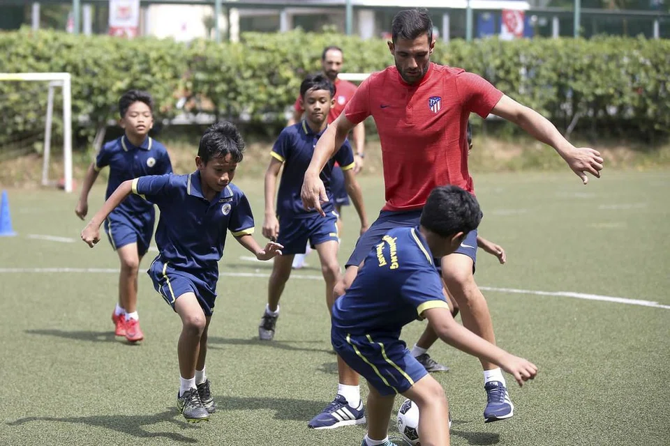 KENA KEPUNG: Penjaga gawang Atletico Madrid, Antonio Adan, meluangkan masa bersama pelajar dari Sekolah Rendah Sembawang dalam satu sesi klinik bola sepak khas baru-baru ini. - Foto ICC 