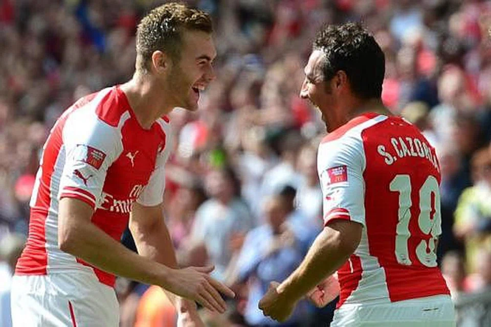 SUDAH MENANG PIALA: Pemain muda yang baru menyertai Arsenal, Calum Chambers (kiri) dengan pemain midfield pasukan, Santi Cazorla, meraikan kejayaan memenangi trofi Perisai Sumbangsih dengan menewaskan Manchester City di Wembley Ahad lalu. - Foto AFP